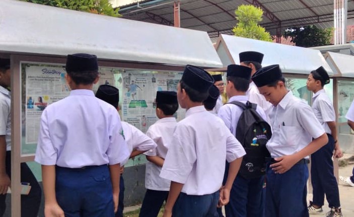 Antusiasme murid membaca koran di halaman madrasah, stand koran ini dipasang sekitar dua minggu lalu